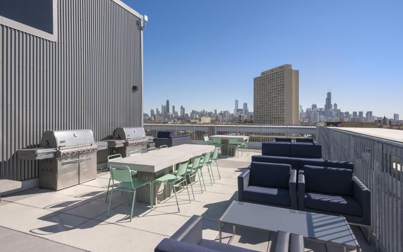a patio with tables and chairs and a body of water in the background
